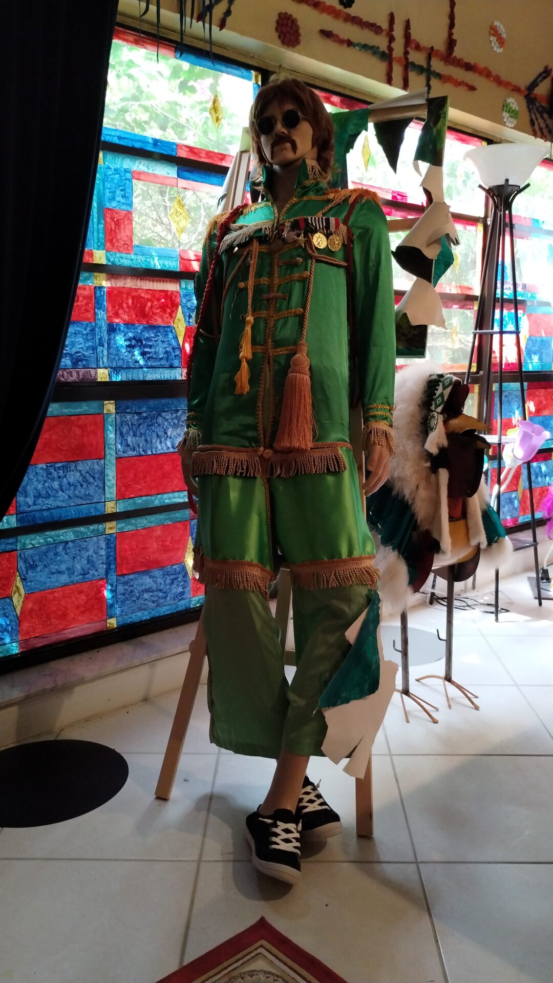Traditional green outfit with tassels displayed in a shop window.
