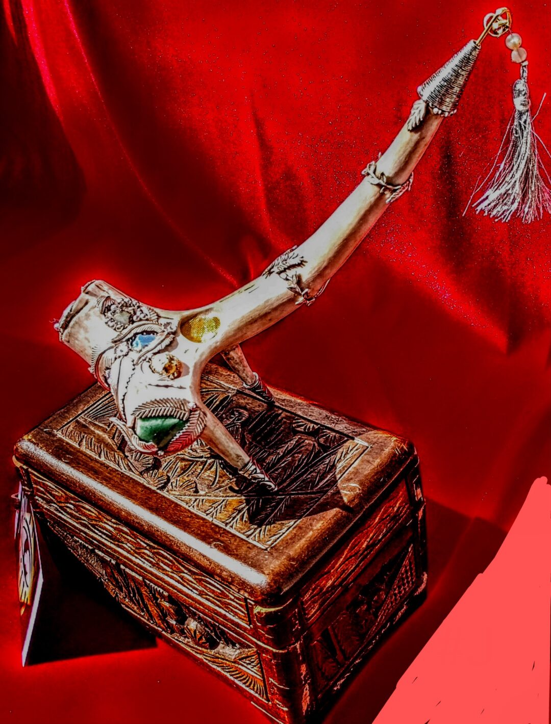 Decorative pipe resting on an ornate box with a red backdrop.