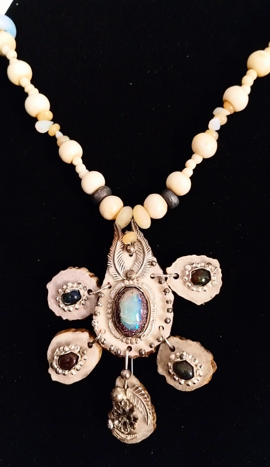 A unique star-shaped necklace with shells, beads, and a central iridescent stone.