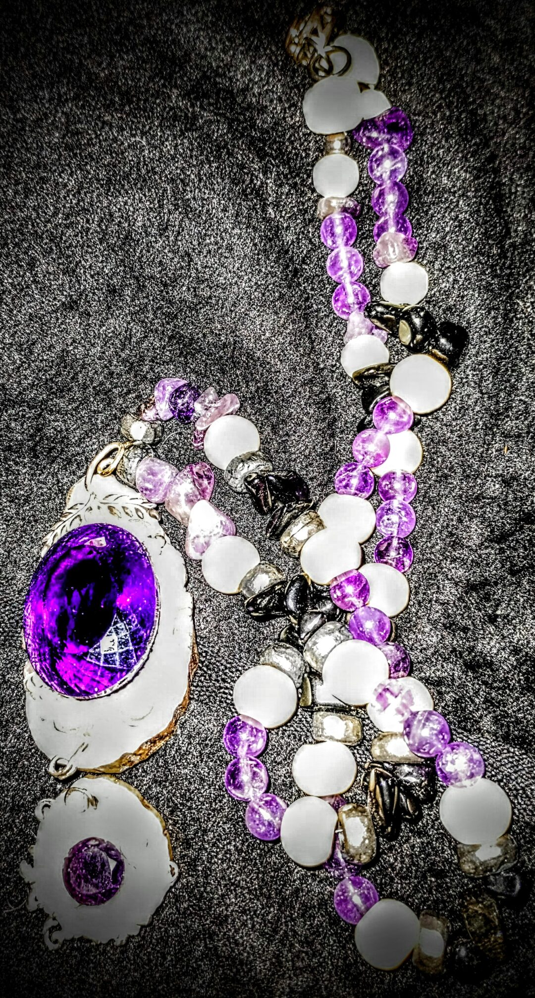 Purple and white beaded necklace with a large oval pendant.