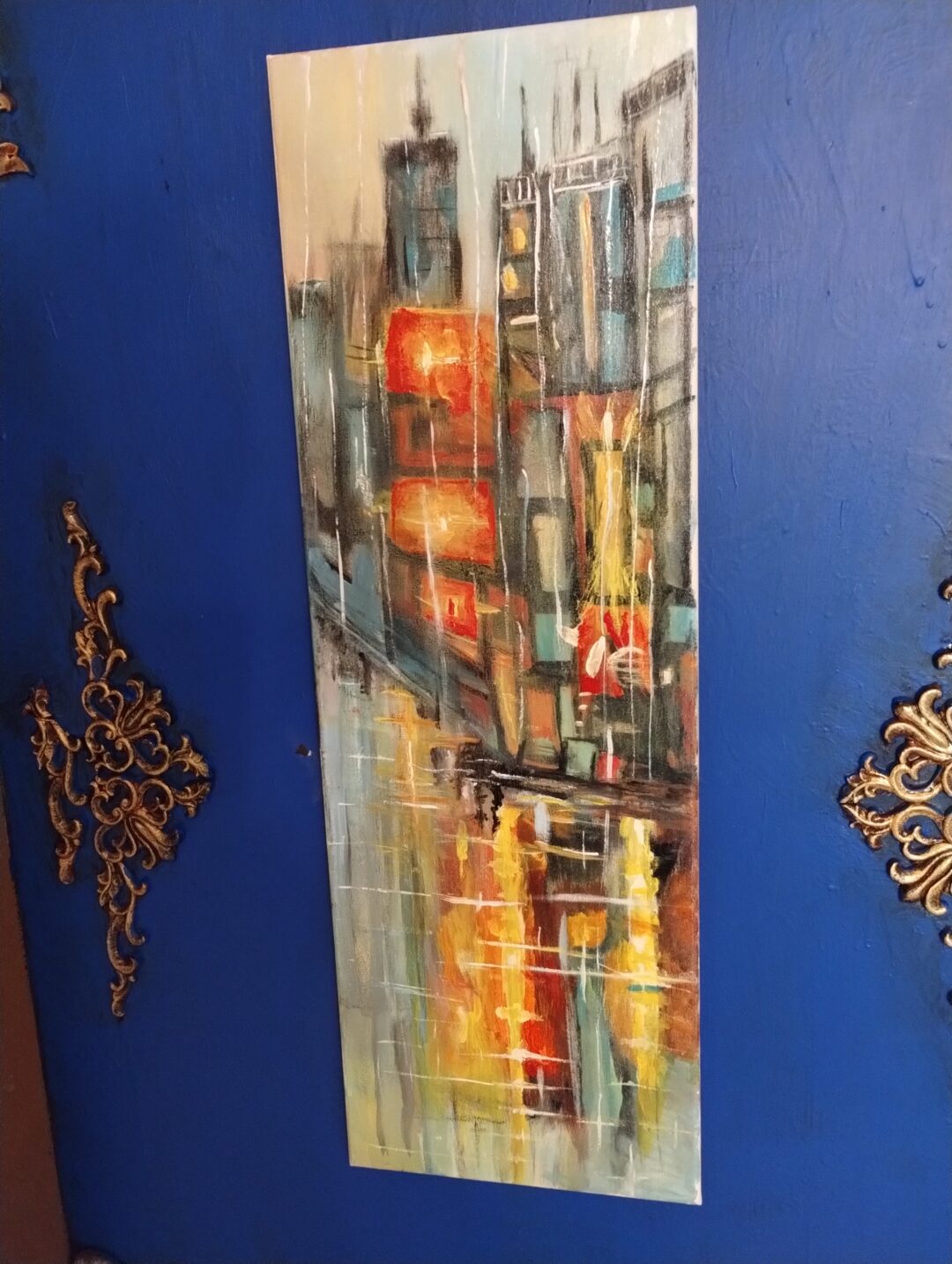Abstract cityscape painting with vibrant colors on a blue wall.