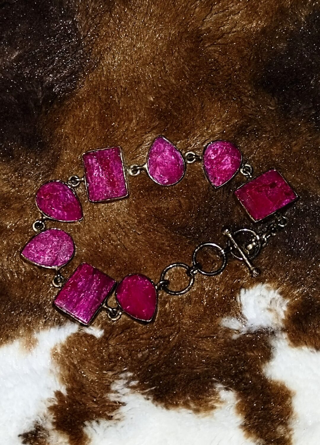 A vibrant pink stone bracelet on a brown textured surface.