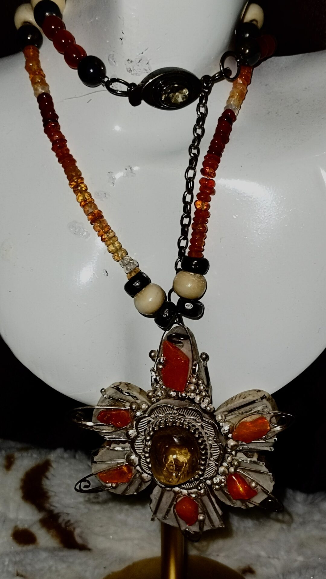 A handcrafted necklace with colorful beads and a floral pendant.